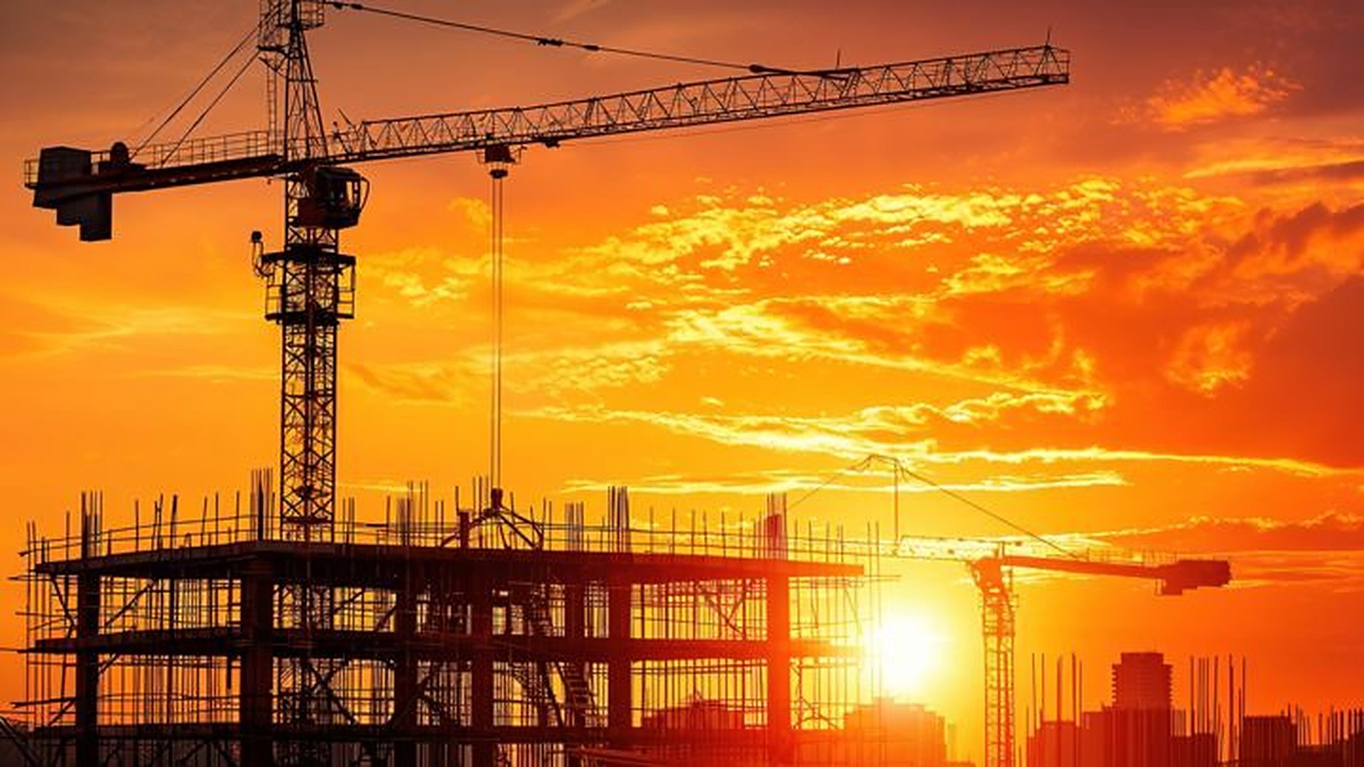 Tower cranes and a building frame at golden hour on a Sovereign Build Inc. site in Georgetown, Guyana
